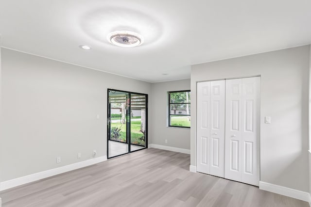 unfurnished bedroom featuring light hardwood / wood-style floors, a closet, and access to exterior