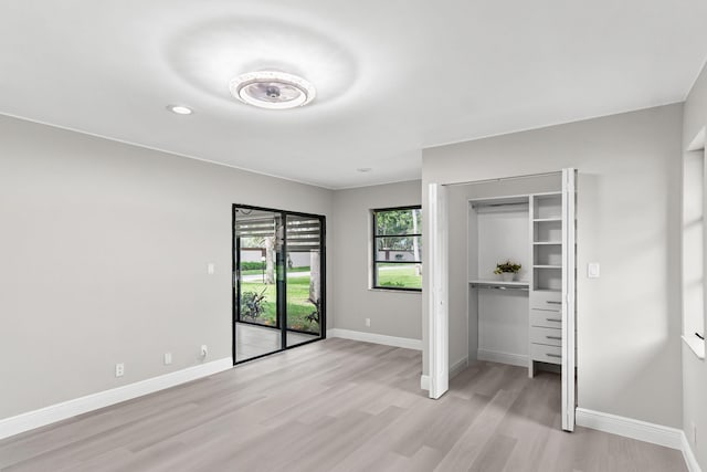 unfurnished bedroom featuring access to outside, light wood-type flooring, and a closet