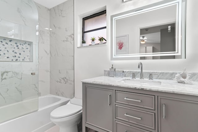 full bathroom featuring ceiling fan, vanity, tiled shower / bath combo, and toilet