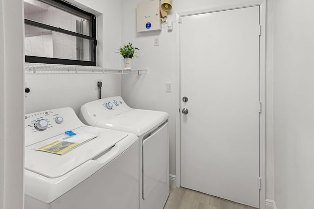 laundry area featuring washing machine and clothes dryer and light hardwood / wood-style flooring