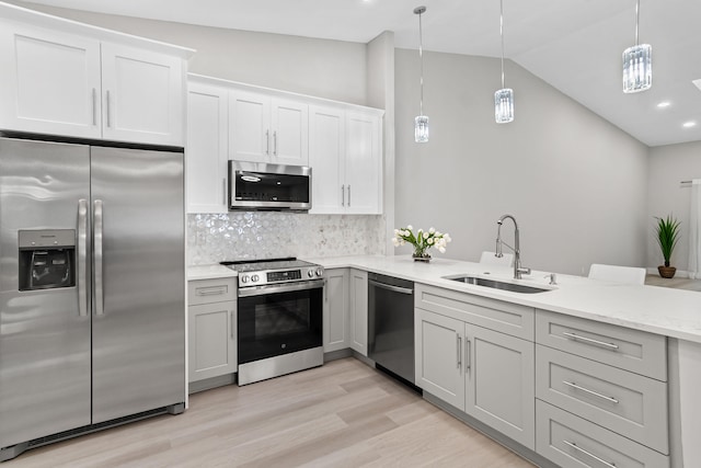 kitchen featuring vaulted ceiling, hanging light fixtures, backsplash, appliances with stainless steel finishes, and sink