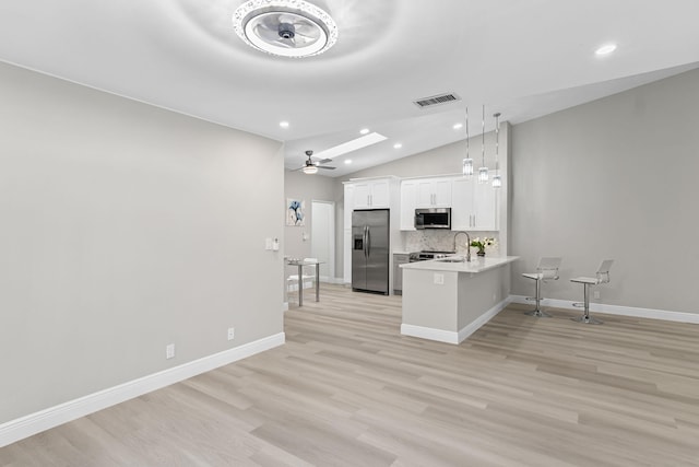 kitchen featuring white cabinetry, vaulted ceiling, ceiling fan, kitchen peninsula, and appliances with stainless steel finishes