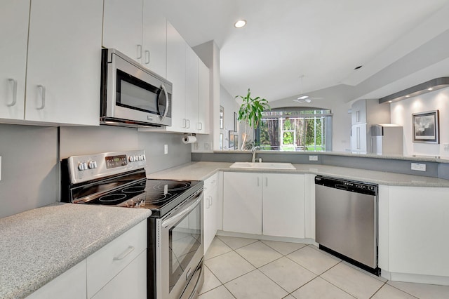 kitchen featuring stainless steel appliances, lofted ceiling, light tile patterned floors, sink, and white cabinetry