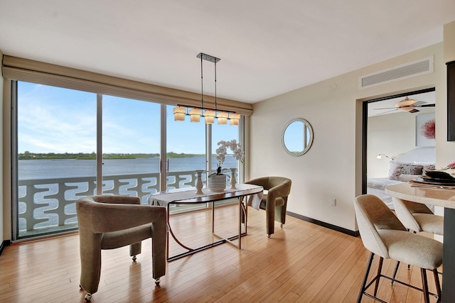 dining room with a wealth of natural light, a water view, and light wood-type flooring