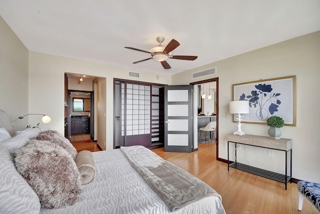 bedroom with wood-type flooring, ensuite bathroom, and ceiling fan