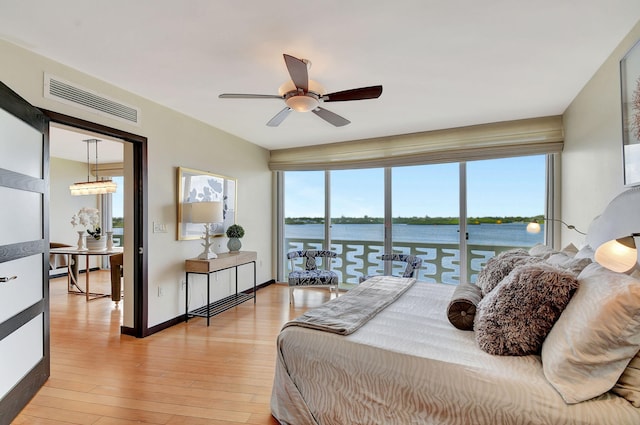 bedroom featuring access to exterior, light hardwood / wood-style floors, a water view, and multiple windows