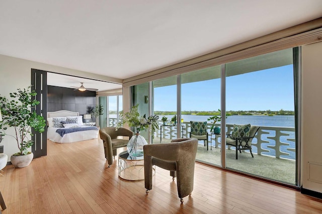 interior space with ceiling fan, a water view, and light hardwood / wood-style floors