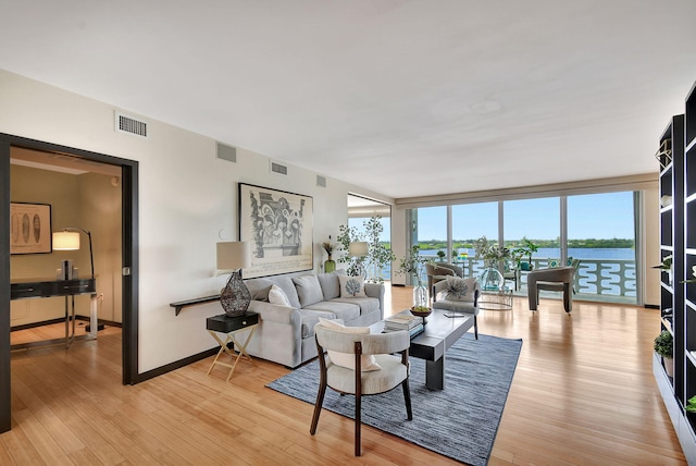 living room featuring a water view, light hardwood / wood-style flooring, and floor to ceiling windows