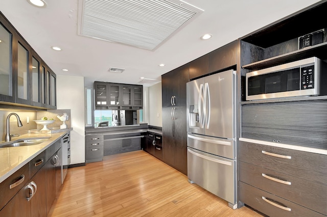 kitchen featuring dark brown cabinetry, sink, light wood-type flooring, and appliances with stainless steel finishes