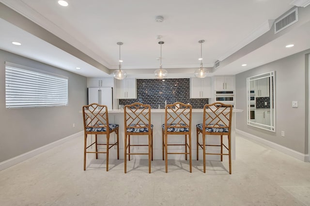 kitchen featuring a kitchen breakfast bar, a raised ceiling, hanging light fixtures, white cabinets, and high end fridge