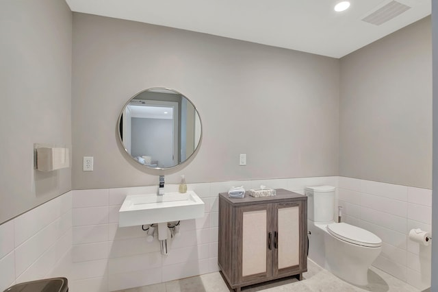 bathroom with tile walls, sink, tile patterned floors, and toilet