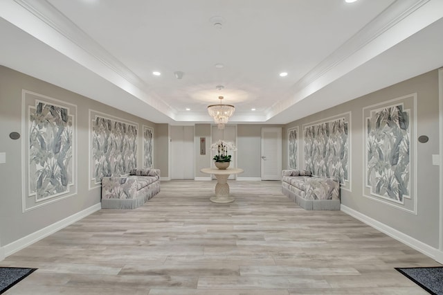 sitting room with a raised ceiling, light wood-type flooring, and an inviting chandelier