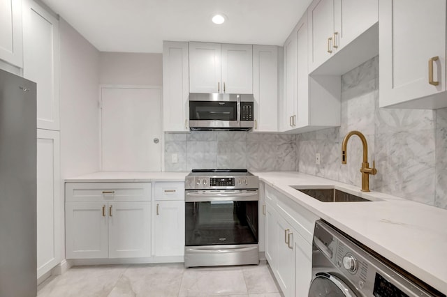 kitchen featuring white cabinets, stainless steel appliances, washer / dryer, decorative backsplash, and sink