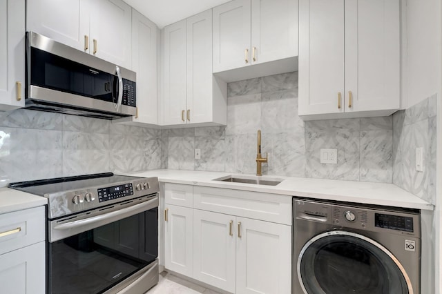 kitchen with white cabinets, stainless steel appliances, washer / dryer, sink, and backsplash