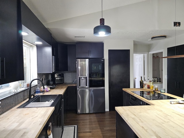 kitchen with wood counters, dark hardwood / wood-style floors, stainless steel refrigerator with ice dispenser, lofted ceiling, and decorative light fixtures