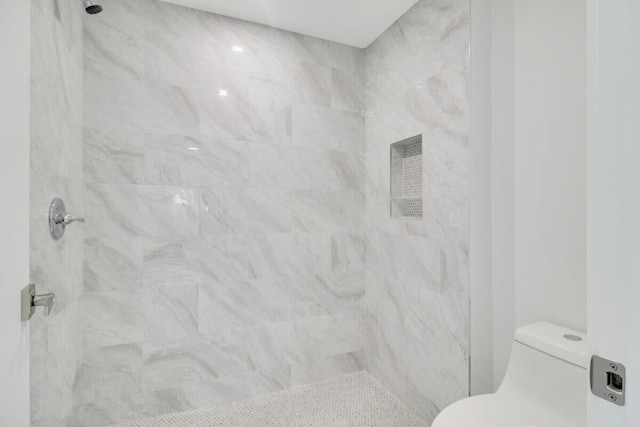 bathroom featuring toilet and a tile shower