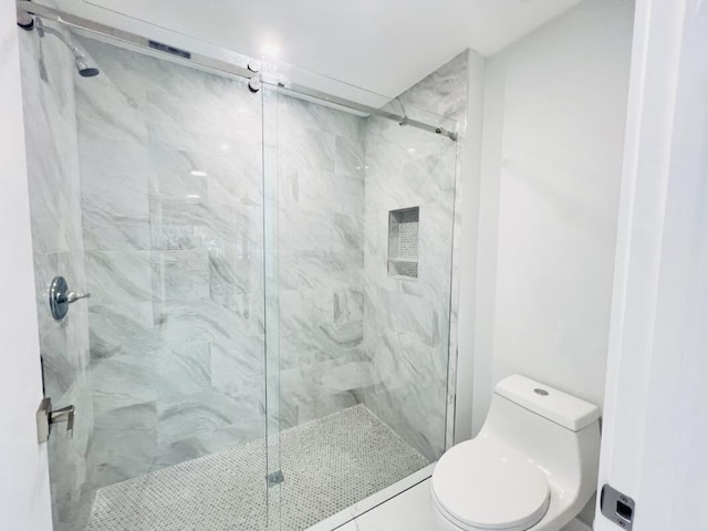 bathroom featuring tile patterned floors, a shower with door, and toilet