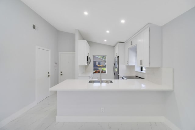 kitchen featuring white cabinetry, sink, kitchen peninsula, lofted ceiling, and appliances with stainless steel finishes