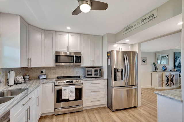 kitchen featuring appliances with stainless steel finishes, decorative backsplash, light hardwood / wood-style floors, and white cabinets