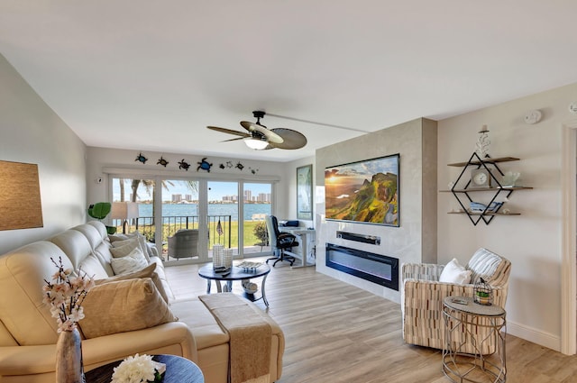 living room featuring a fireplace, ceiling fan, and light hardwood / wood-style flooring