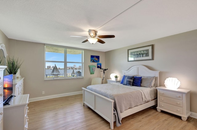 bedroom featuring light hardwood / wood-style floors, a textured ceiling, and ceiling fan