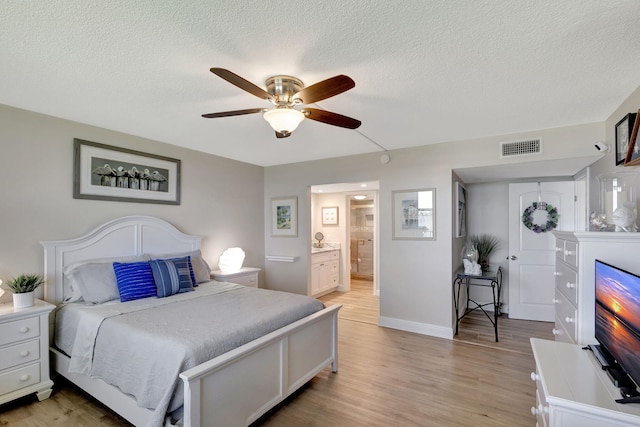 bedroom featuring ensuite bath, a textured ceiling, ceiling fan, and light hardwood / wood-style flooring