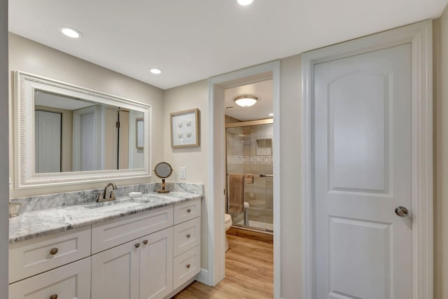 bathroom with toilet, vanity, hardwood / wood-style floors, and walk in shower