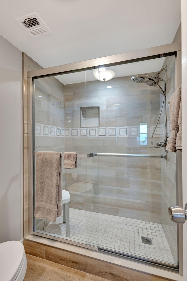 bathroom featuring toilet, hardwood / wood-style floors, and a shower with shower door