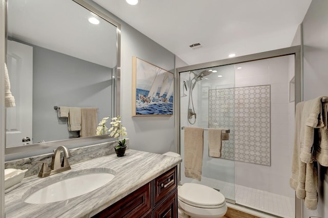 bathroom with an enclosed shower, vanity, and toilet