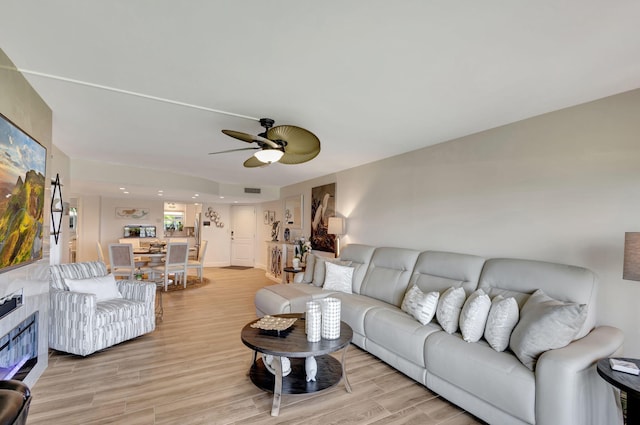 living room with a ceiling fan and light wood-type flooring