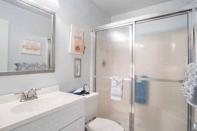 bathroom with toilet, a shower with shower door, and vanity