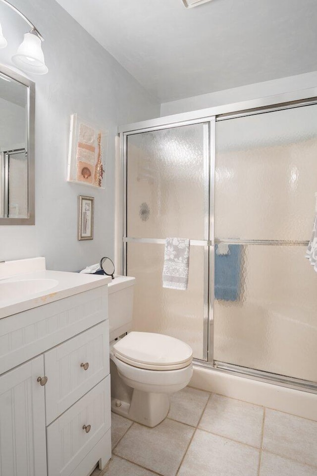 bathroom with vanity, walk in shower, toilet, and tile patterned flooring