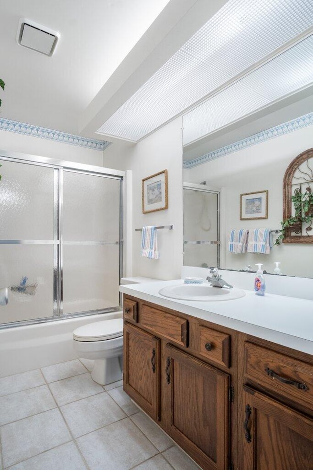 full bathroom featuring vanity, combined bath / shower with glass door, toilet, and tile patterned flooring