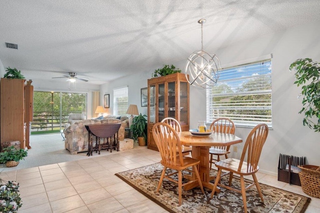 tiled dining room featuring a textured ceiling and ceiling fan with notable chandelier