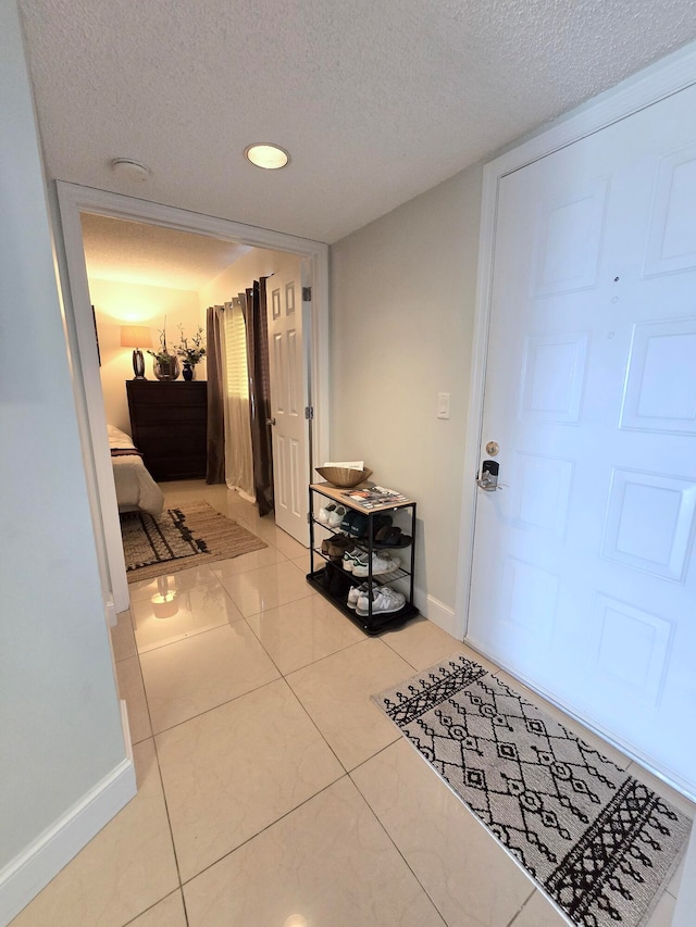 hall featuring a textured ceiling and light tile patterned flooring