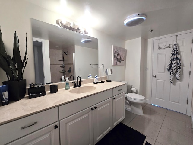 bathroom featuring toilet, vanity, tile patterned floors, and tiled shower