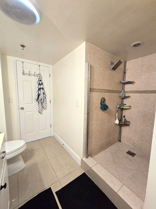 bathroom with a tile shower, vanity, toilet, and tile patterned flooring