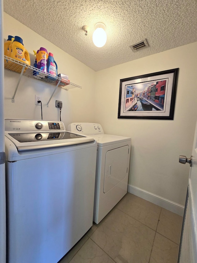 laundry area with independent washer and dryer, a textured ceiling, and light tile patterned floors