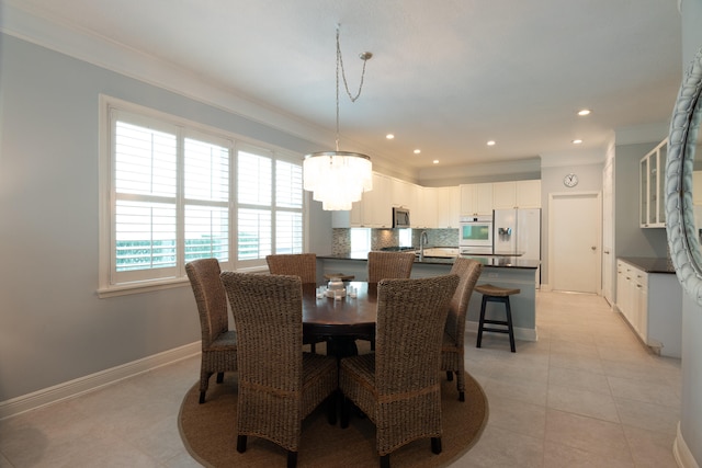 tiled dining area featuring a notable chandelier, ornamental molding, and sink