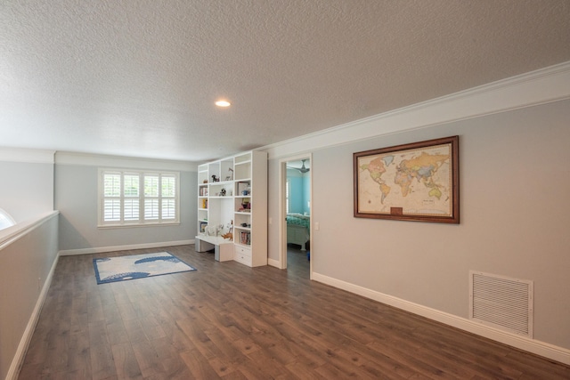 empty room featuring ornamental molding, dark wood-type flooring, and a textured ceiling