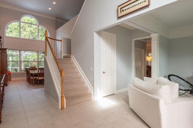 stairway with crown molding, tile patterned floors, and a high ceiling