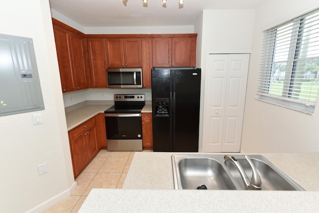 kitchen with appliances with stainless steel finishes, light tile patterned flooring, electric panel, and sink