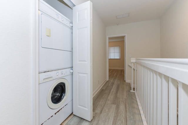 clothes washing area featuring light hardwood / wood-style flooring and stacked washer and clothes dryer