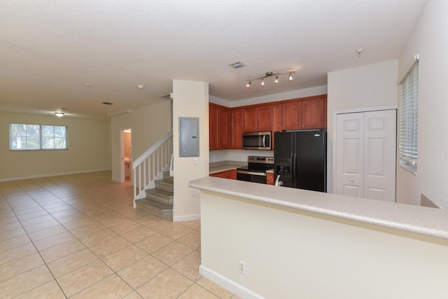 kitchen with stainless steel appliances, electric panel, light tile patterned flooring, and a textured ceiling