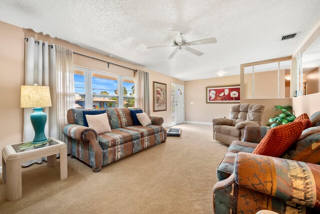 carpeted living room featuring ceiling fan and a textured ceiling