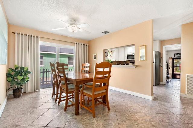 dining space with a textured ceiling, light tile patterned floors, and ceiling fan