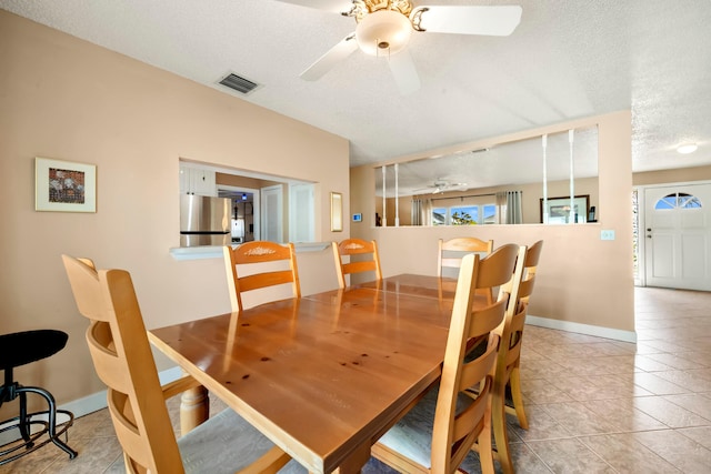 dining space with a textured ceiling, light tile patterned floors, and ceiling fan