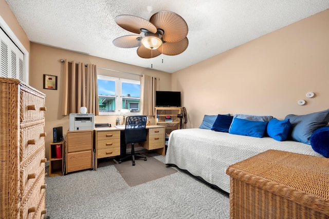 carpeted bedroom featuring a textured ceiling, ceiling fan, and a closet