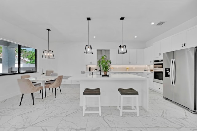 kitchen featuring a kitchen bar, a kitchen island, white cabinetry, appliances with stainless steel finishes, and decorative light fixtures