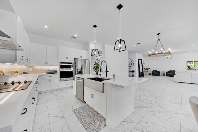 kitchen featuring a center island with sink, sink, appliances with stainless steel finishes, hanging light fixtures, and white cabinets